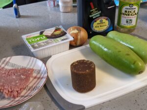ground pork on plate, palm sugar and opo squash on cutting board, tofu, onion, soy sauce, rice vinegar