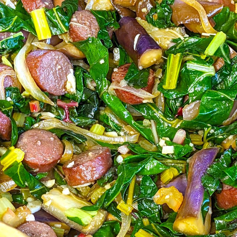 beef sausage, eggplant, onions, and swiss chard sauteed in a pan