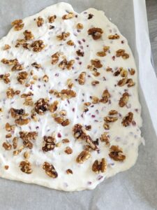 yogurt bark with pomegranate and walnuts on sheet pan before freezing