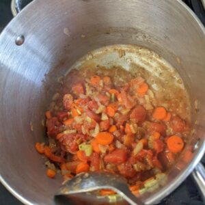 onions, carrots, celery, canned tomatoes, and seasonings in pot