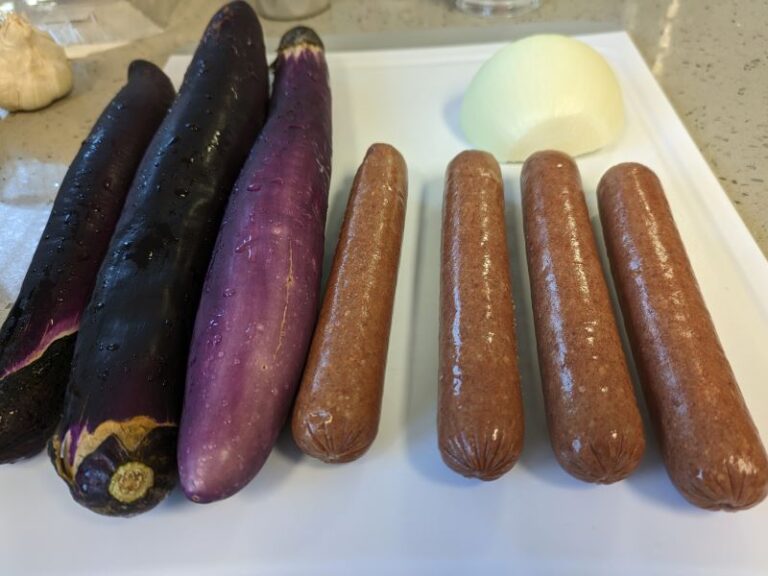Teton Water Ranch beef sausages next to long eggplant on cutting board
