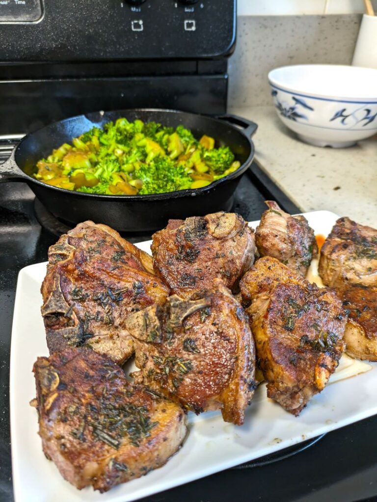 seared lamb chops for a crowd on a serving plate with cast iron pan in the background