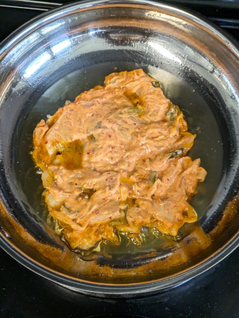 kimchi pancake in a stainless steel pan before flipping